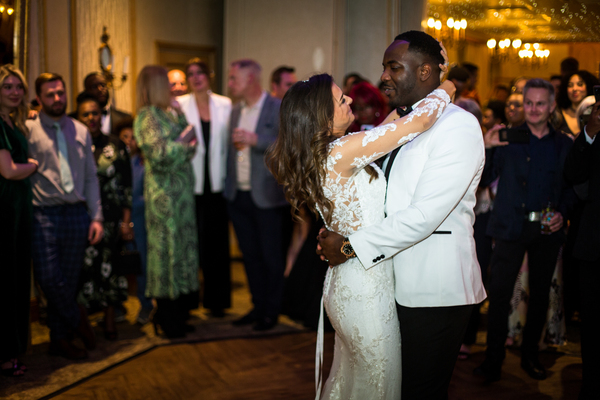 Claire and Ant, arms around each other during the first dance. Guests look on, smiling 